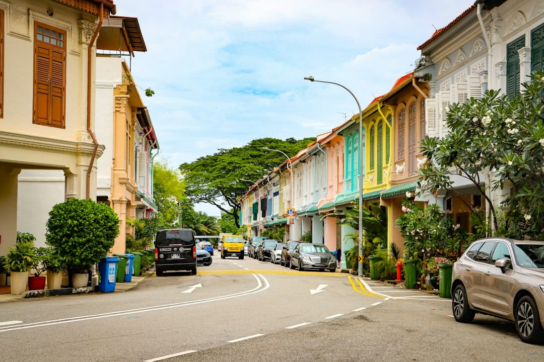 Colourful shophouses and cars along a busier Telok Kurau edge street